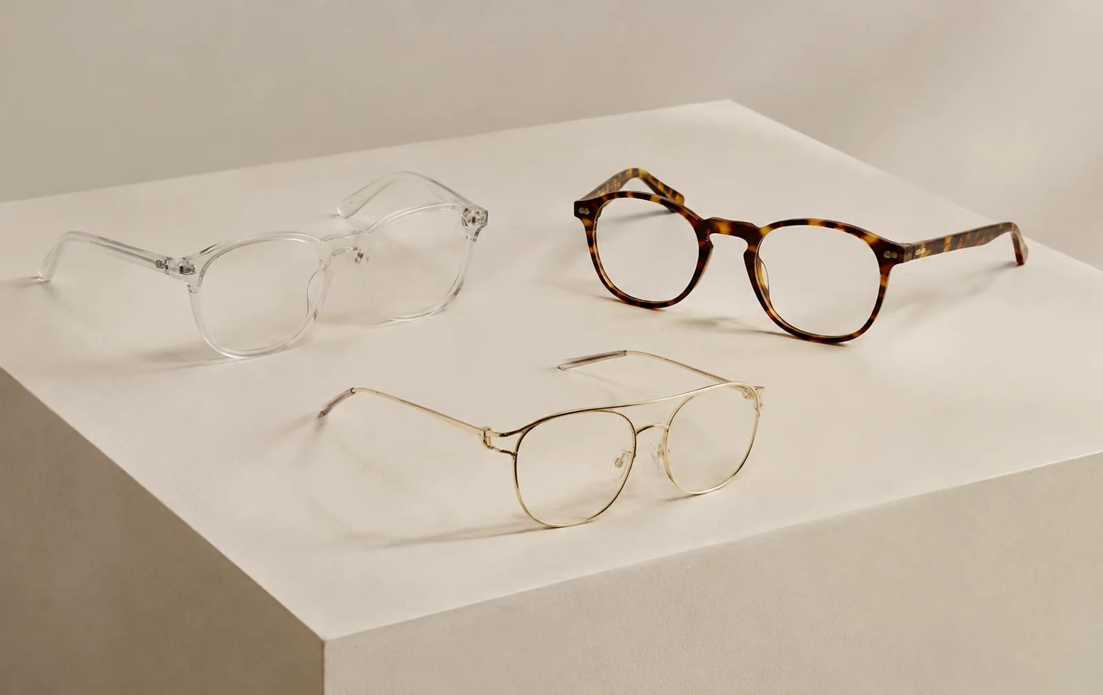 Clear acetate, tortoiseshell and gold wire frames on a plinth
